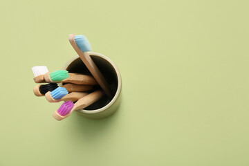 Glass with different toothbrushes on green background, closeup