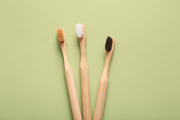 Different wooden toothbrushes on green background, closeup