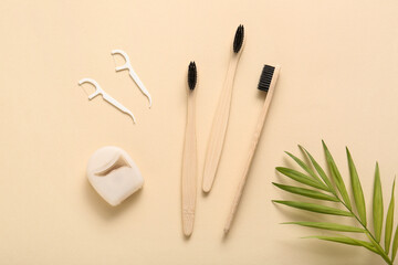 Composition with wooden toothbrushes, dental floss and toothpicks on beige background, closeup