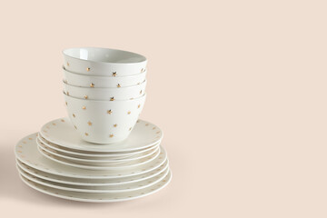 Stack of clean white dishes with golden stars on beige background, closeup