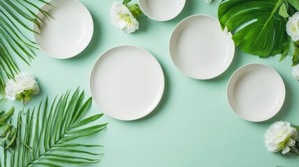 Elegant Table Setting with White Plates, Tropical Leaves, and White Flowers on Mint Green Background