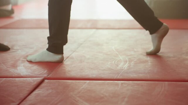 Boxer footwork with athletes wearing socks on red gym mat showing stance, posture, agility, and coordination during combat training emphasizing movement, precision, discipline, and physical control