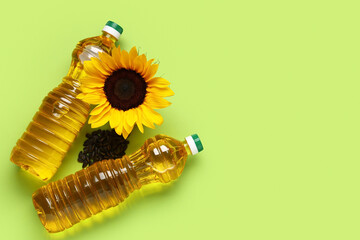 Naklejka premium Bottles of oil with sunflower and seeds on green background