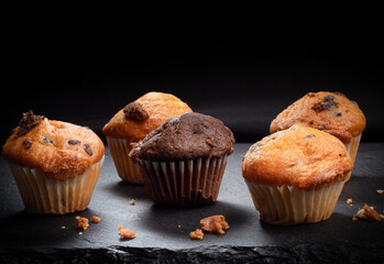 Chocolate and vanilla muffins on dark slate plate with crumbs
