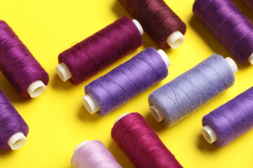 Set of different thread spools on yellow background, closeup