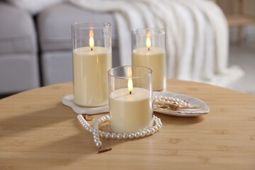 Decorative LED candles and pearl jewellery on wooden table indoors