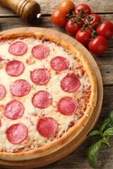 Delicious pepperoni pizza and ingredients on wooden table, closeup