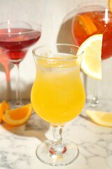 Glasses of tasty cocktails with garnish on white marble table, closeup