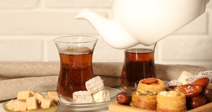 Pouring freshly brewed Turkish tea into glass at table, closeup