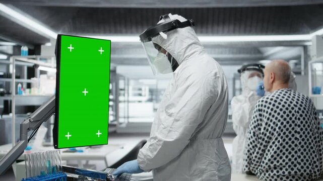 Vertical green screen next to black medic in hazmat suit observing contagious epidemic in lab, examining patient with serious symptoms. Preventing global disaster and health crisis. Camera A.