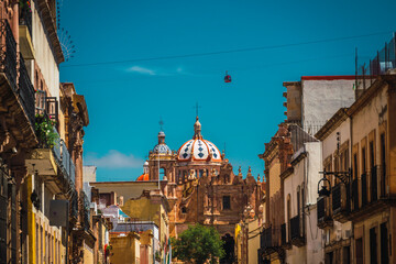 Fototapeta premium Santo Domingo Church accompanied by many colonial-style quarry houses and in the sky the cable car of Zacatecas, Mexico.