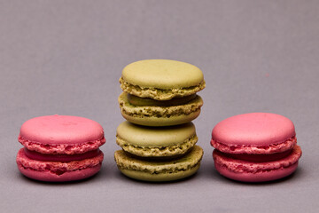 Three macarons pink green and yellow on gray background