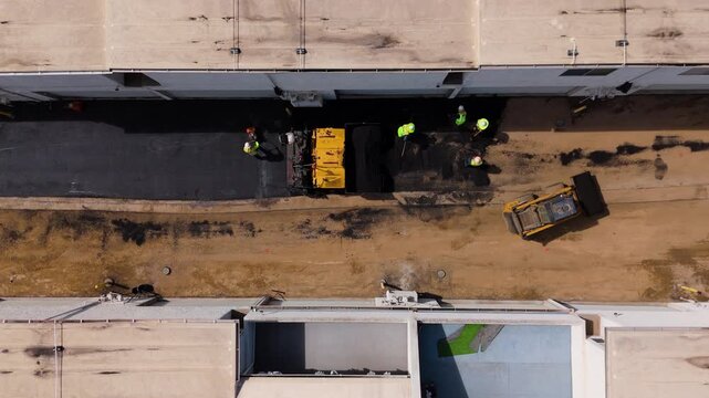 Aerial view of road construction workers paving asphalt with heavy machinery in Los Angeles