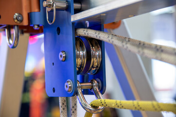 A blue and silver pulley is attached to a yellow rope