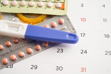 Pregnancy test and birth control pills on calendar, contraception health and medicine.