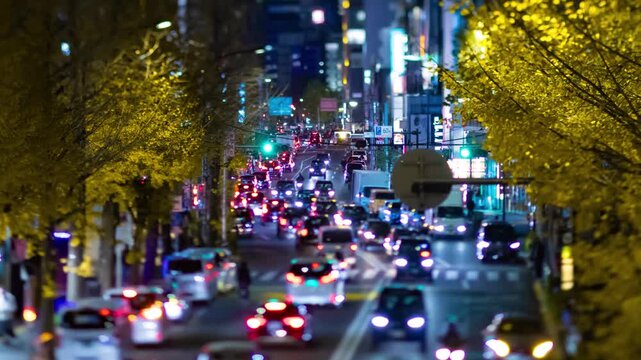 A night timelapse of miniature traffic jam on the city street with yellow leaves
