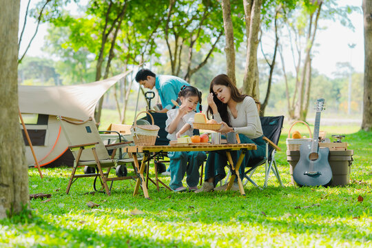 Happy Asian family having a picnic in the park during summer vacation. The boy enjoys his trip with his parents in the park. Beautiful nature.