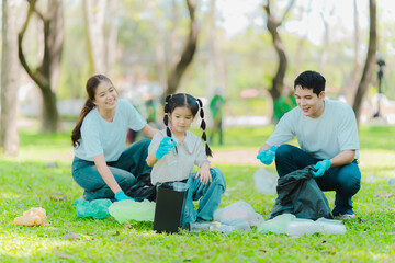 Fototapeta premium Volunteers collect trash in the park, clean up the area, volunteer concept, charity, people and ecology, Asian family collecting plastic waste, World Cleanup Day