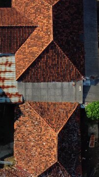 The roof of a building is covered in red tiles. The roof is slanted and has a triangular shape