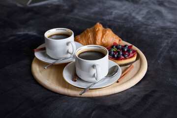Savor the delightful combination of coffee and pastry beautifully arranged on a wooden platter