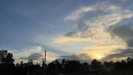 Sunset Through Clouds Over Rural Landscape with Power Lines and Distant Moon View