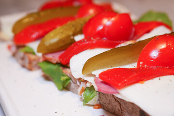 Hearty sandwich topped with vegetables on a white plate
