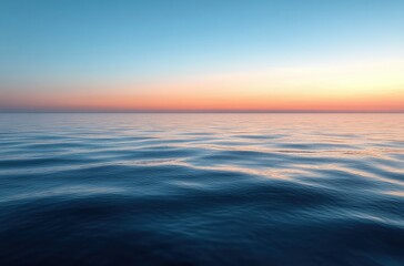 Obraz premium Calm ocean waves under a clear sky at sunset with vivid gradient colors from blue to orange creating a peaceful and serene atmosphere