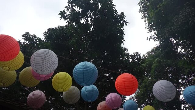 Many beautiful colorful Chinese lanterns hang in the wind in the garden