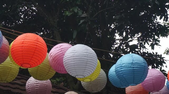 Many beautiful colorful Chinese lanterns hang in the wind in the garden
