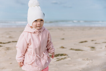 Cute child girl on ocean coastline. Winter holidays concept.