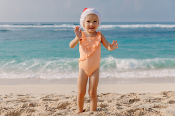 Little child girl in beach with Christmas hat. Portrait of happy smiling girl