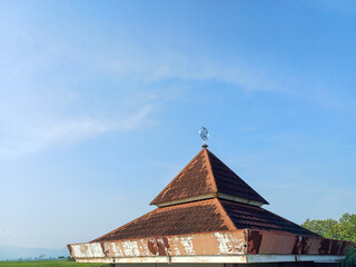 Obraz premium Bright morning view of a simple mosque roof and dome against a clear blue sky in Indonesia, Southeast Asia. Focus on peace, spirituality, Islamic culture, and morning light.