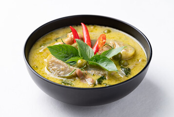 Thai green curry chicken in black bowl on white background