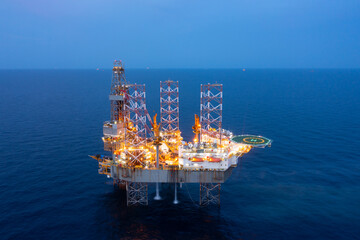 Aerial view of offshore jack up rig and offshore platform during sunset for oil and gas exploration and production.