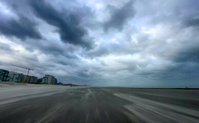 A deserted beach road under a dramatic, cloudy sky, evoking feelings of solitude and nature's power.