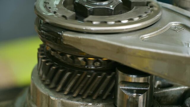 Extreme close up car gearbox or transmission mechanism with rotating metal helical gears and synchronizers, showing complexity, precision of automotive engineering. Rotating metal transmission gears