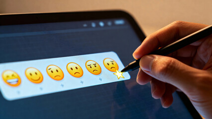 Hand selecting a star rating on a digital device screen with emoji feedback options