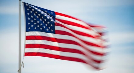The national flag of the United States of America billows gracefully in a strong breeze, its vibrant red, white, and blue colors blurred by the motion
