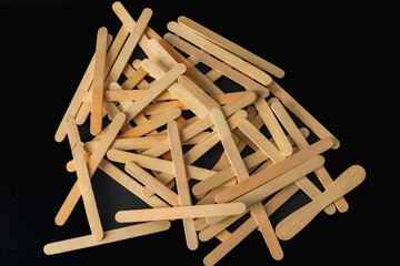A pile of wooden sticks with a black background. The sticks are all different sizes and are scattered around the image.