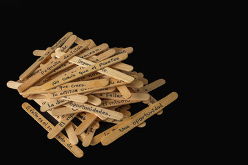 A pile of wooden skewers with Spanish writing on them. The skewers are stacked on top of each other, and the writing is in a foreign language. Scene is one of curiosity and intrigue.