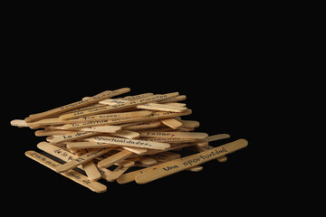 A pile of wooden sticks with Spanish words written on them. The sticks are arranged in a way that they form a message. Scene is one of creativity and playfulness.