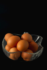 A bowl of eggs is sitting on a black background. The eggs are all different sizes and are arranged in a way that makes them look like they are in a basket.