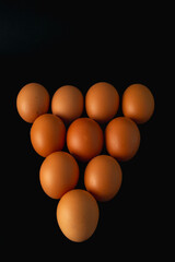 A row of nine eggs are arranged in a triangle. The eggs are all the same size and color.