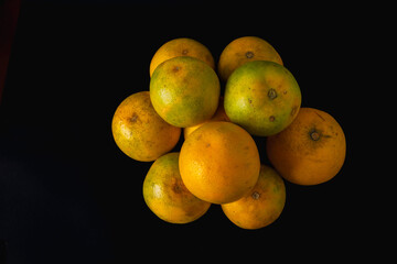 A bunch of oranges are piled on top of each other. The oranges are all different sizes and colors, but they all have a similar texture. The image has a warm, inviting feeling.