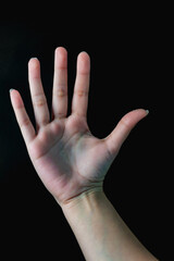 A hand with the thumb up and the other fingers down. The hand is on a black background.