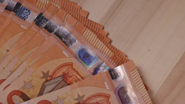 Close up of vibrant euro banknotes laid out on a wooden table showing details of currency design in a cozy setting at dusk