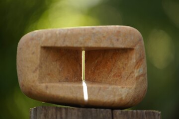 Sunlight streams through a carved stone with a natural green background