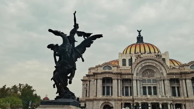 A bronze Pegasus sculpture stands in front of the Palacio de Bellas Artes, showing the building&rsquo;s domed roof and ornate facade under a cloudy sky in Mexico City.