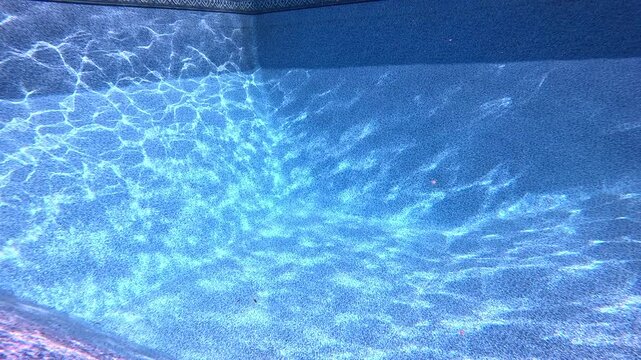 Empty swimming pool bottom. Sun goes behind clouds and ripples become less visible.