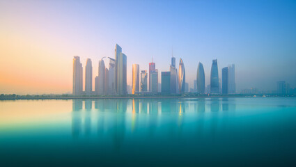 Fototapeta premium Majestic skyscrapers rise above the calm waters, reflecting the first light of dawn. The peaceful scene captures the beauty of urban architecture in a serene location